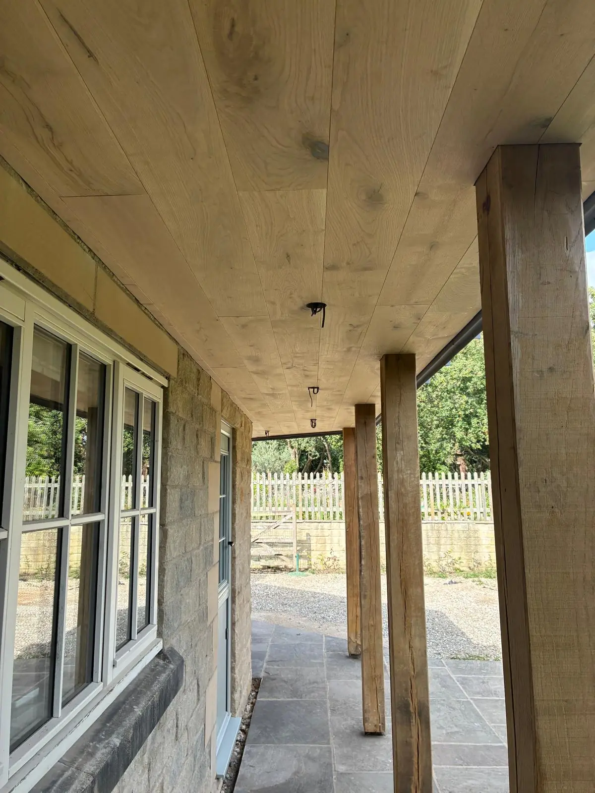 Covered walkway beneath the canopy with oak posts and stone flags